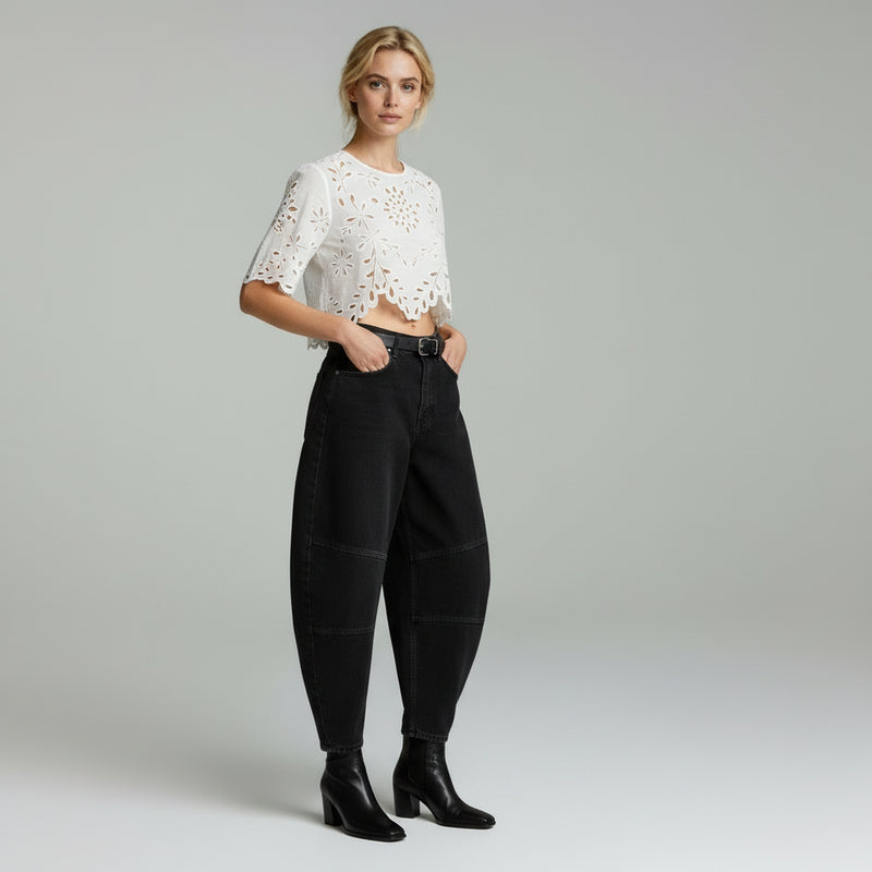 lady in white top and balloon style jeans on a plain background