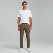 man wearing white t-shirt paired with beige trousers on a plain background