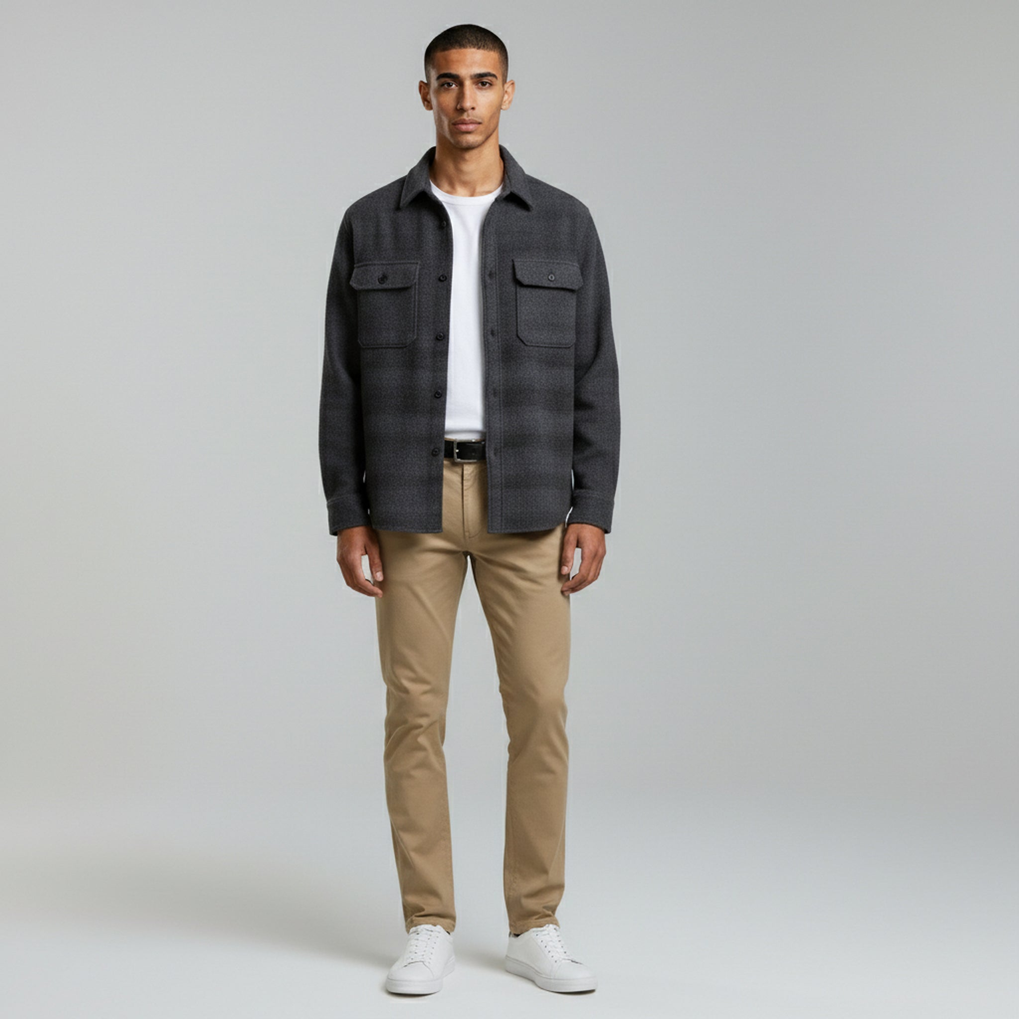 man wearing white inner t-shirt with jacket paired with khaki jeans and white shoes on a plain background