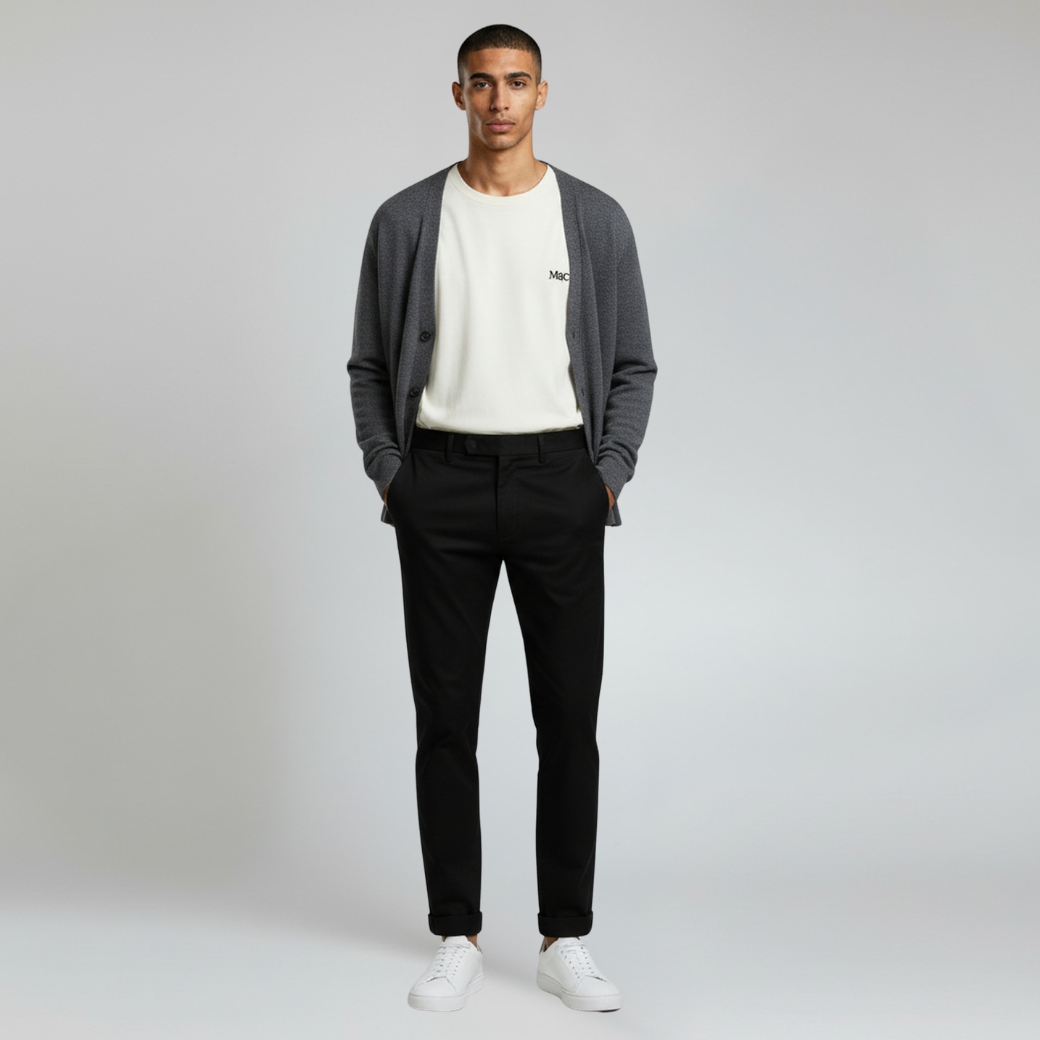 man wearing white shirt inner and sweater paired with black pants and white shoes on a plain background