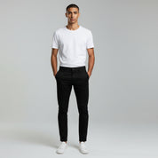 man wearing white shirt top and black pants on a plain background