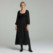 woman wearing black maxi dress paired with black boots on a plain background