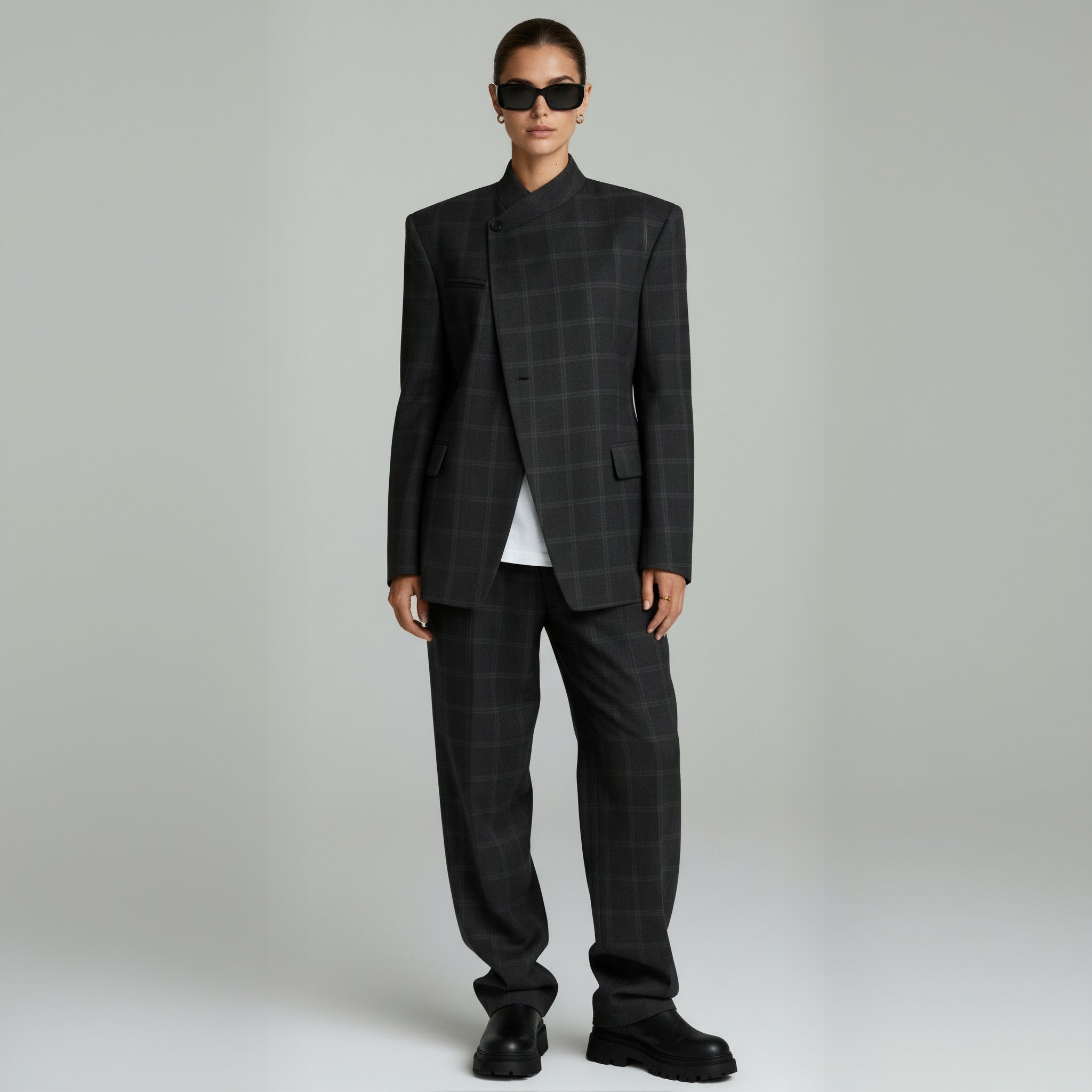 woman wearing black plaided blazer coat and pants on a plain background