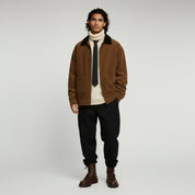 man wearing brown jacket and black pants on a plain background