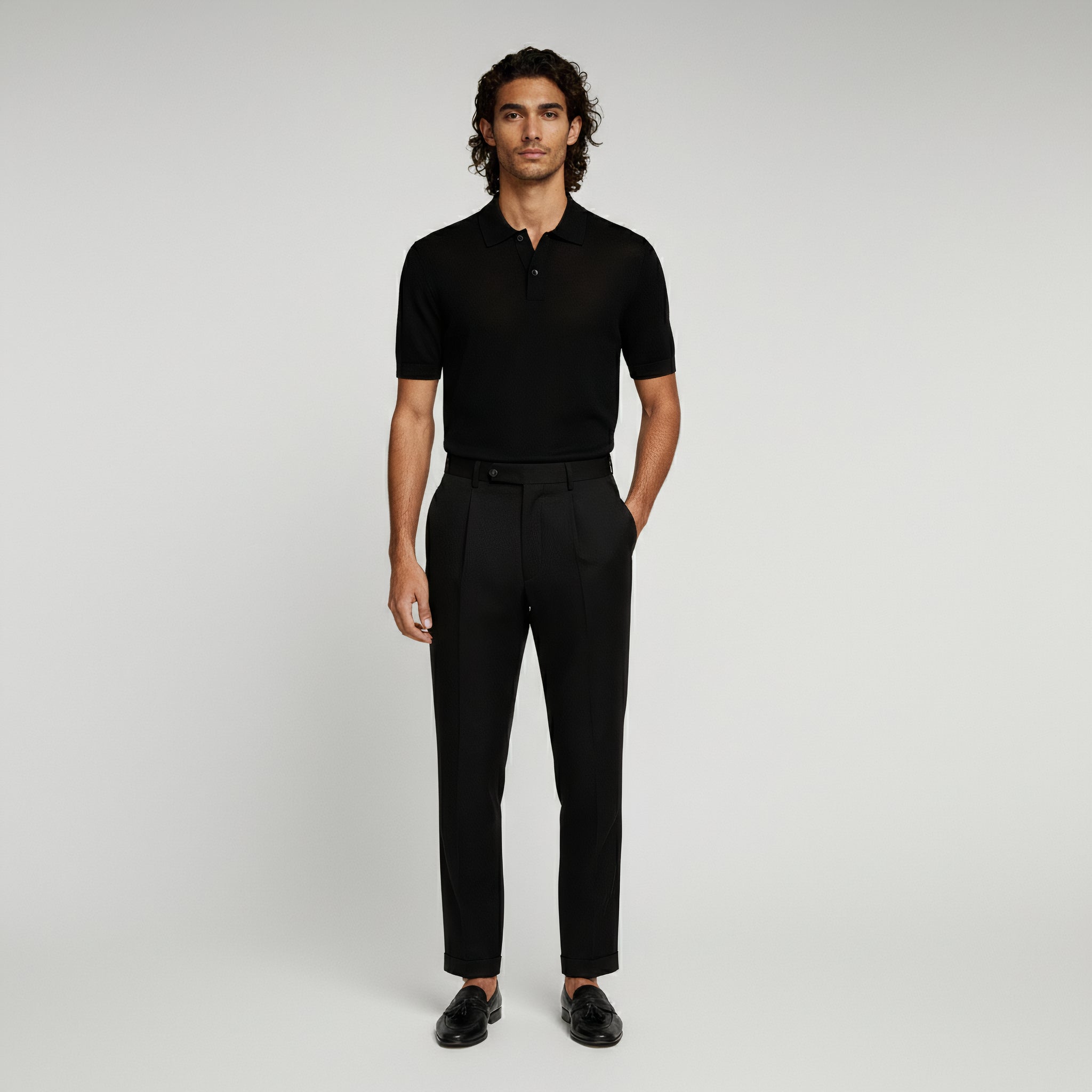 man wearing black polo shirt and black trousers on a plain background