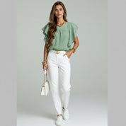lady in green silk blouse and white pants on a plain background