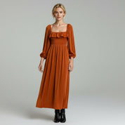 lady in dark orange maxi dress on a plain background