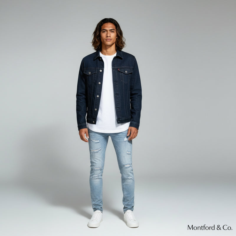 man in white shirt with denim jacket paired with slim fit jeans on a plain background