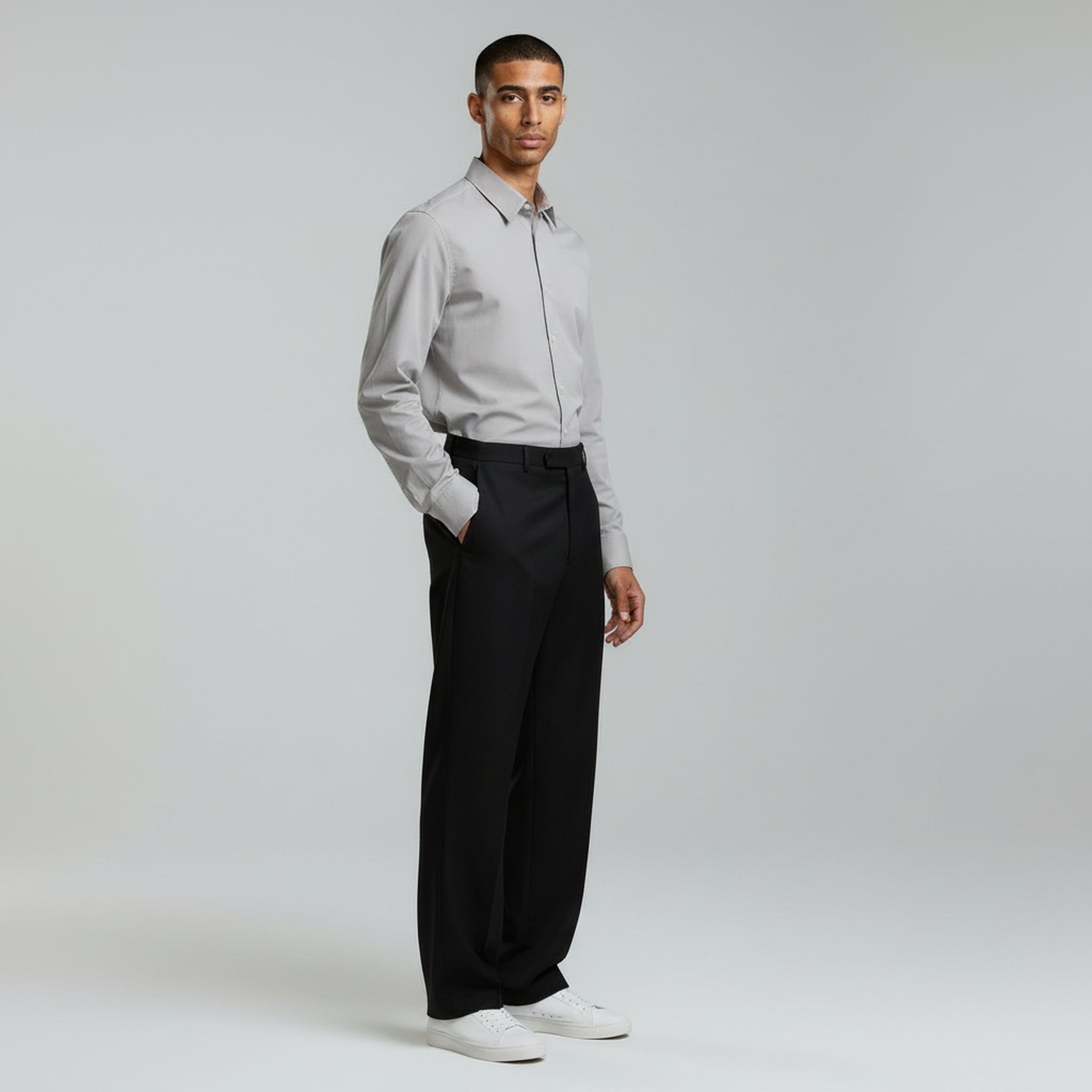 man wearing gray polo long sleeved and black elastic pants on a plain background