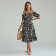 woman wearing black floral maxi dress on a plain background