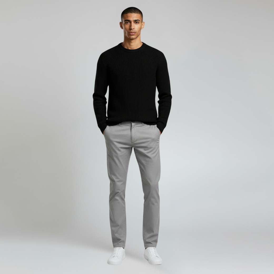 man wearing black sweatshirt paired with gray pants on a plain background