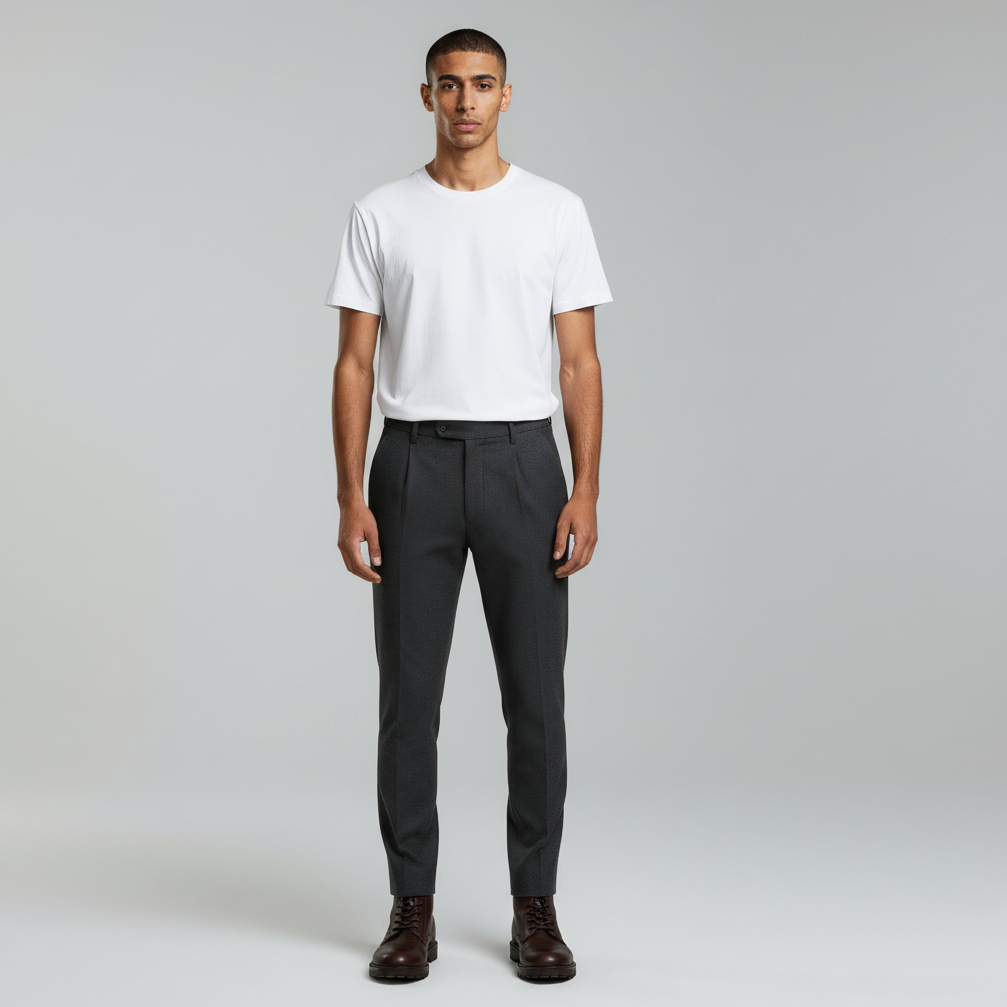 man wearing white t-shirt paired with gray trousers on a plain background