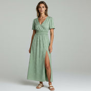 woman wearing green flowy maxi dress on a plain background