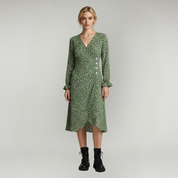 woman wearing Green Long sleeve midi dress paired with lack boots on a plain background