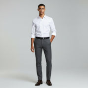 man wearing white long sleeve polo and grey pants on a plain background