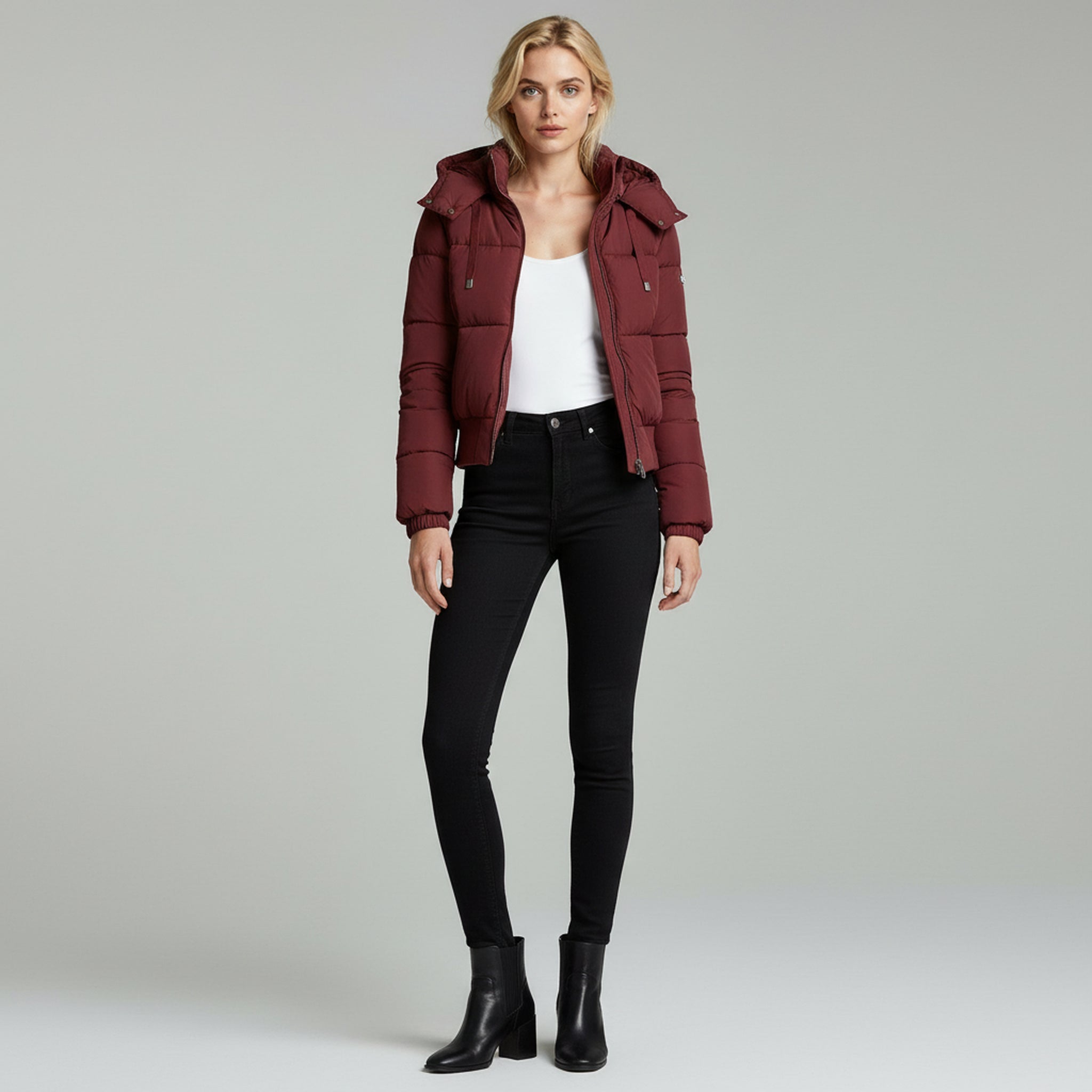 woman wearing white inner top with hooded jacket paired with black pants on a plain background
