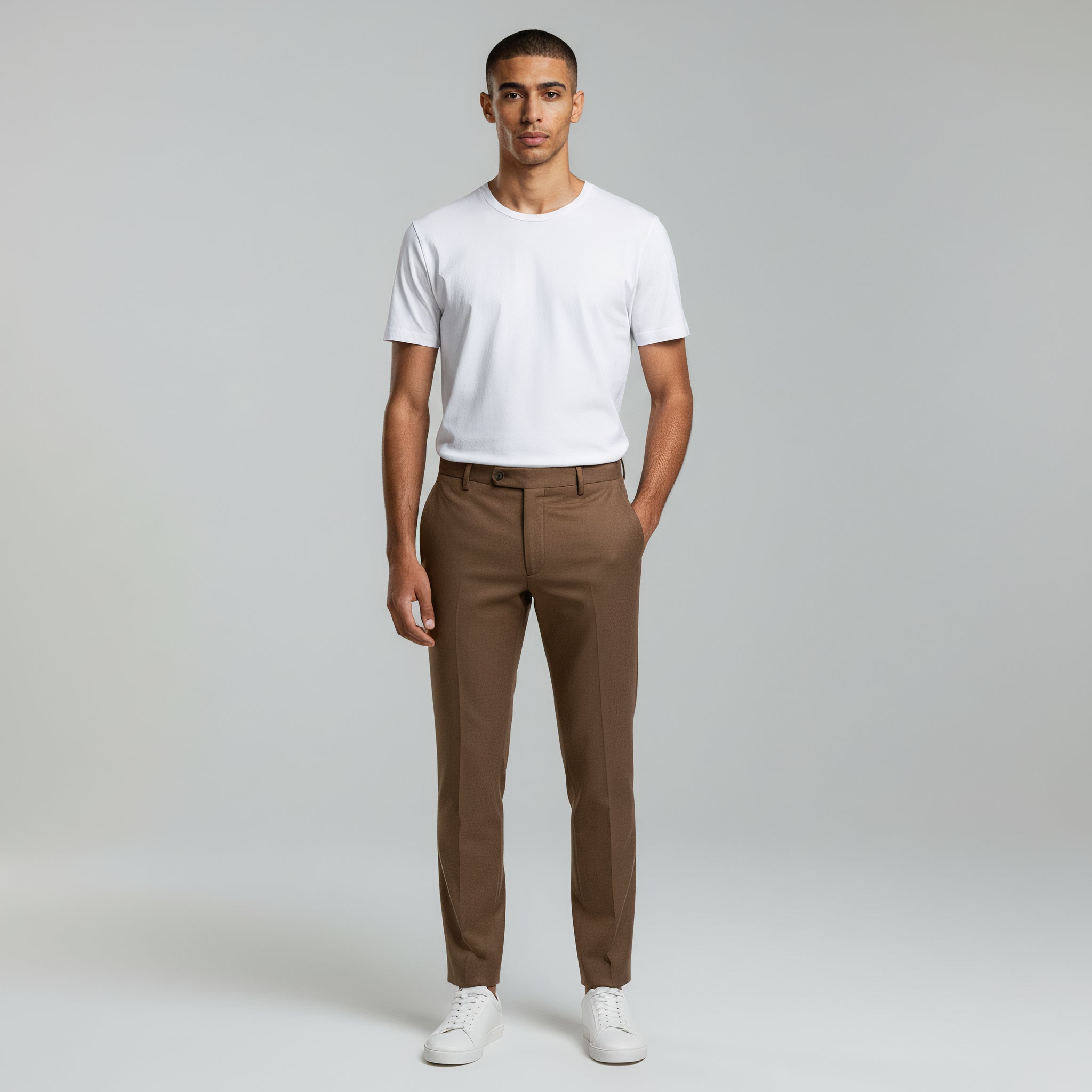 man wearing white shirt top paired with khaki pants on a plain background