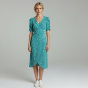 woman wearing light blue puff sleeve midi dress paired with white shoes on   a plain background