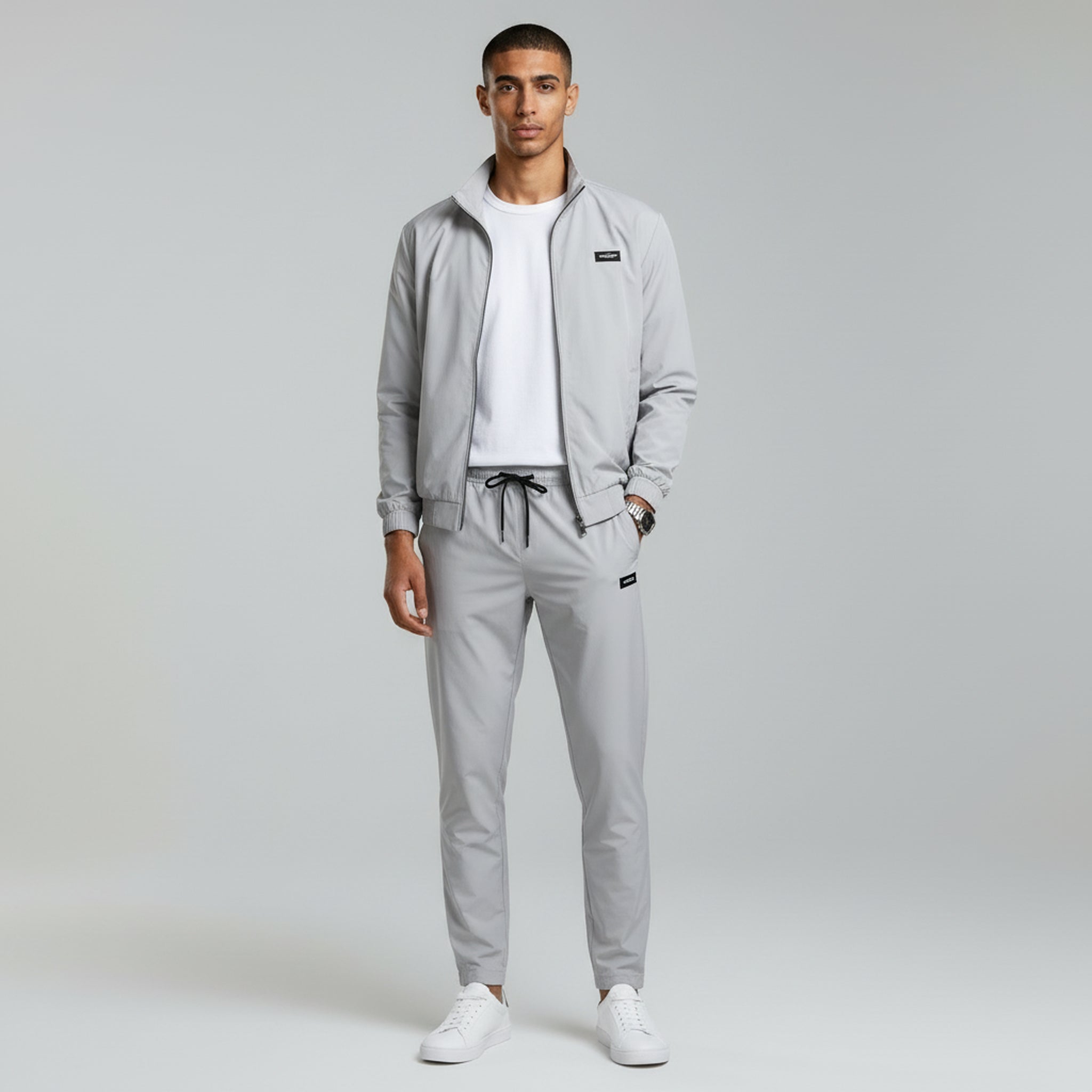 man in grey jacket and light grey trousers on a plain background