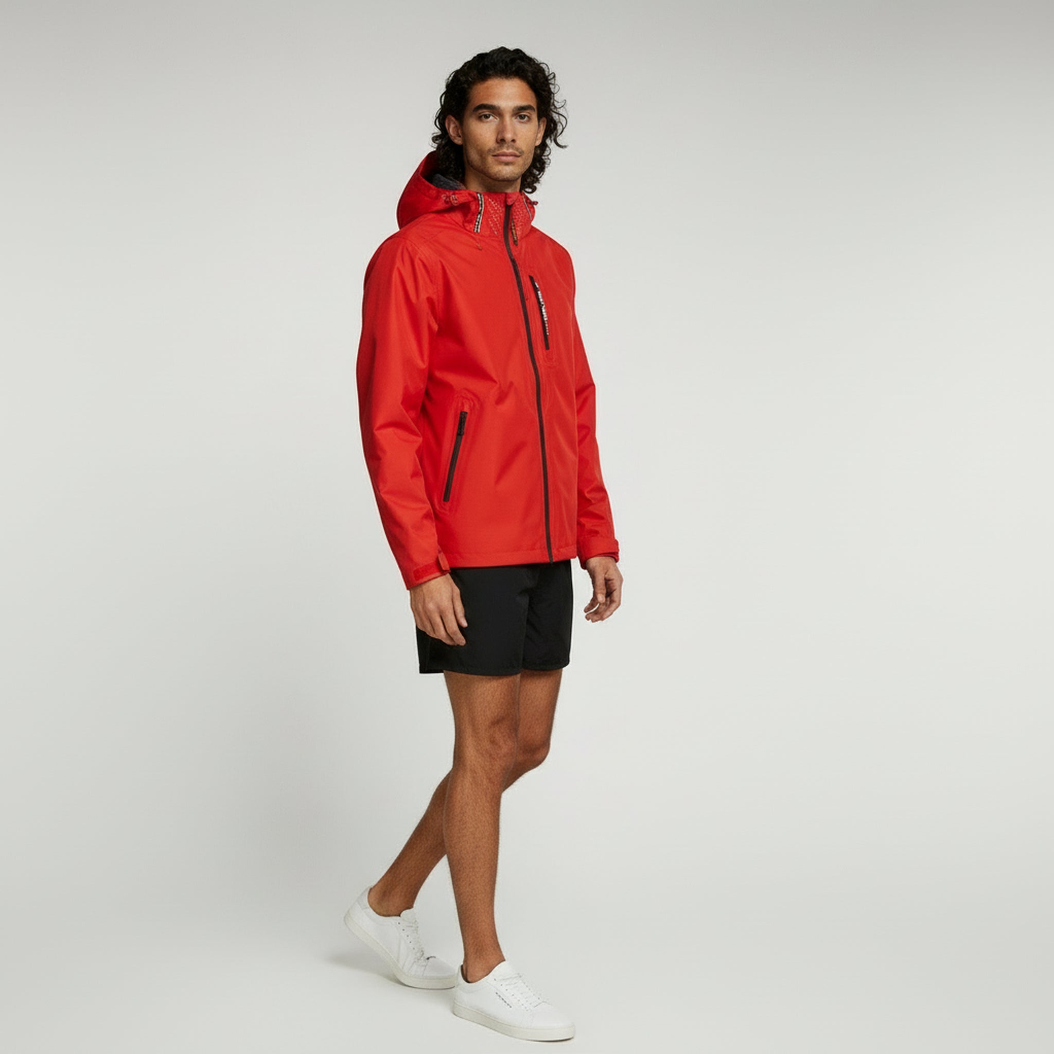 man wearing red lightweight jacket and shorts on a plain background