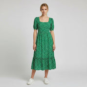 woman wearing green maxi dress on a plain background