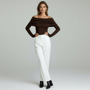 lady in brown off shoulder top and white pants on a plain background