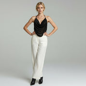 lady wearing black sleeveless top and white pants on a plain background