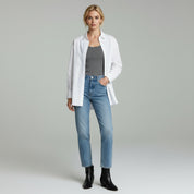 woman wearing grey inner top and white loose long sleeve paired with slim blue jeans on a plain studio background
