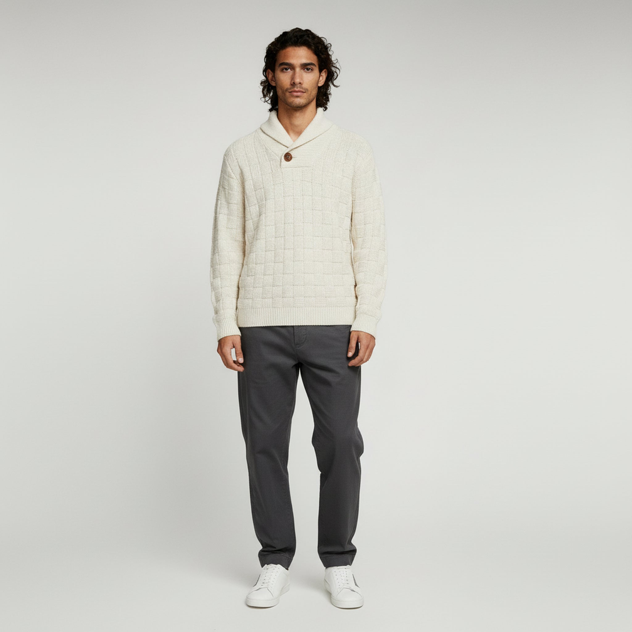 man wearing white sweater and gray pants on a plain background