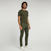 man wearing dark green shirt and green stretchable fit pants on a plain background