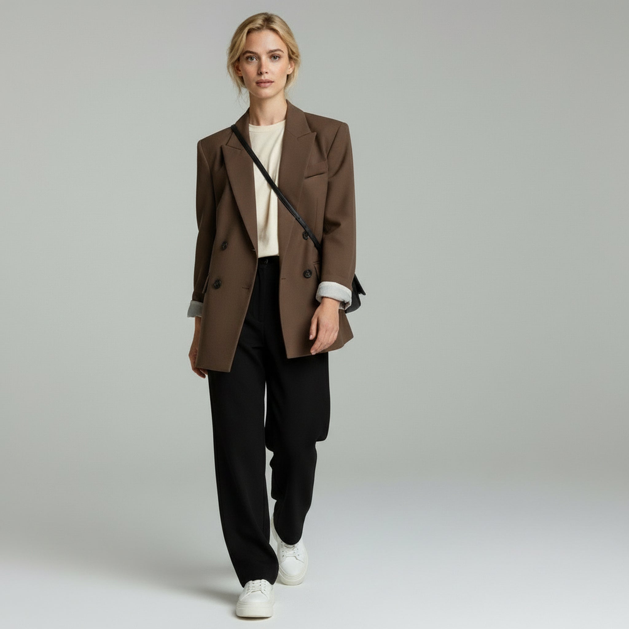 lady wearing brown loose blazer and black pants on a plain background