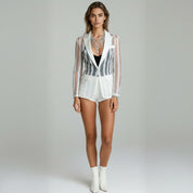 woman wearing black inner top with white blazer coat paired with white shorts on a plain background