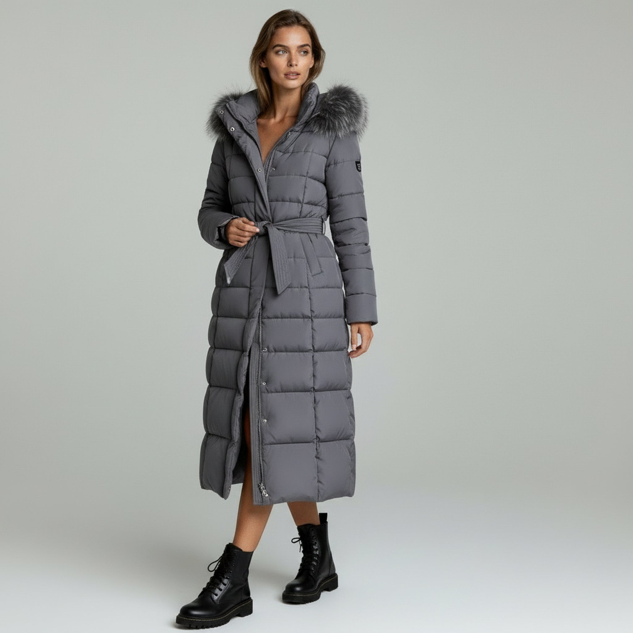 lady wearing grey winter long padded coat on a plain background