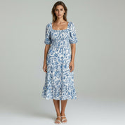 woman wearing blue flowy maxi dress on a plain background