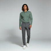 man wearing green long sleeve polo and grey pants on a plain background