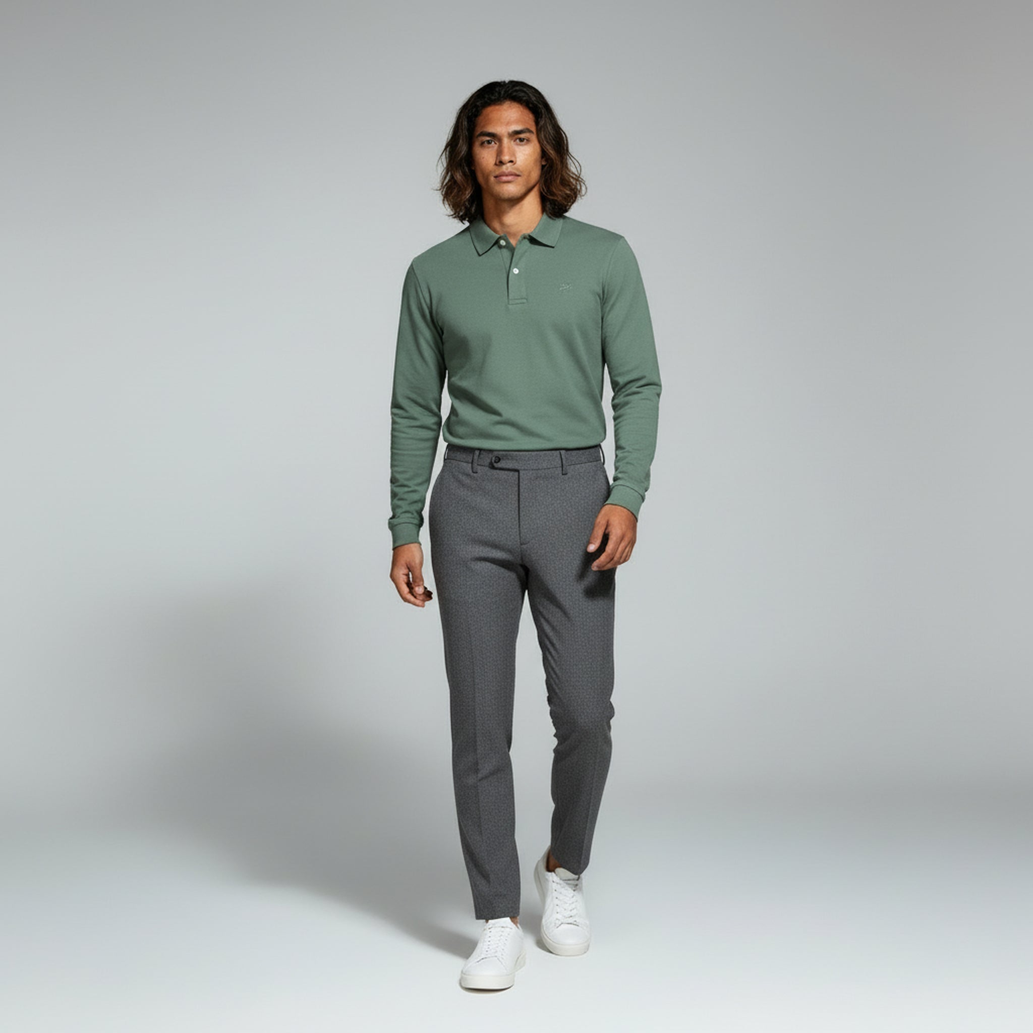 man wearing green long sleeve polo and grey pants on a plain background