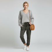 woman wearing gray sweater and grey trousers on a plain background