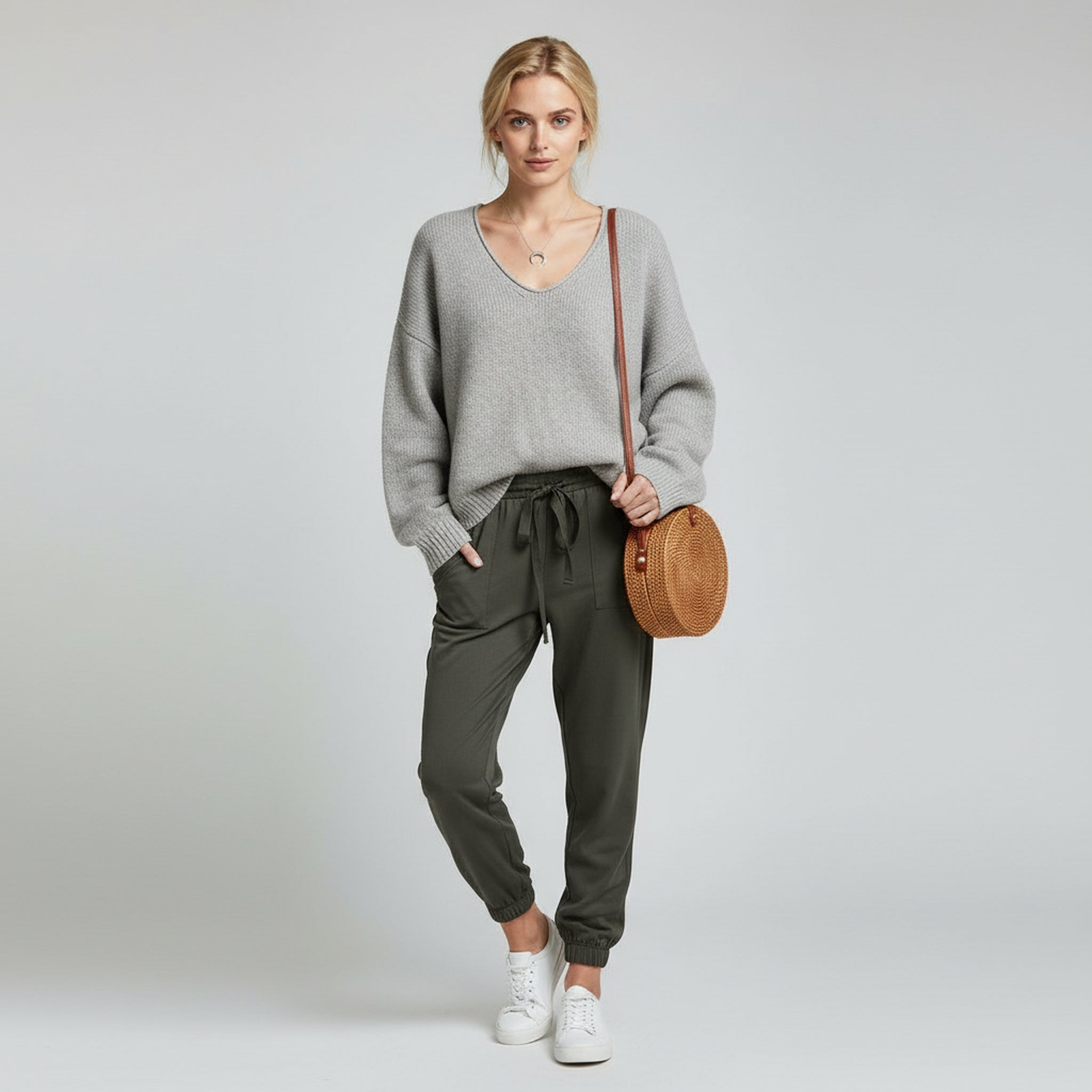 woman wearing gray sweater and grey trousers on a plain background