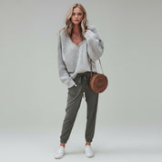 woman wearing light gray sweater and pants on a plain background